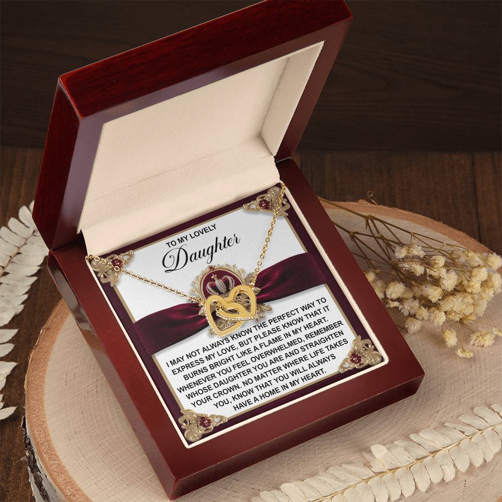 A wooden box opens to reveal the Daughter-A Flame - Interlocking Hearts Necklace, crafted with cubic zirconia crystals and a rose gold finish, resting on a card with a heartfelt message for a daughter.