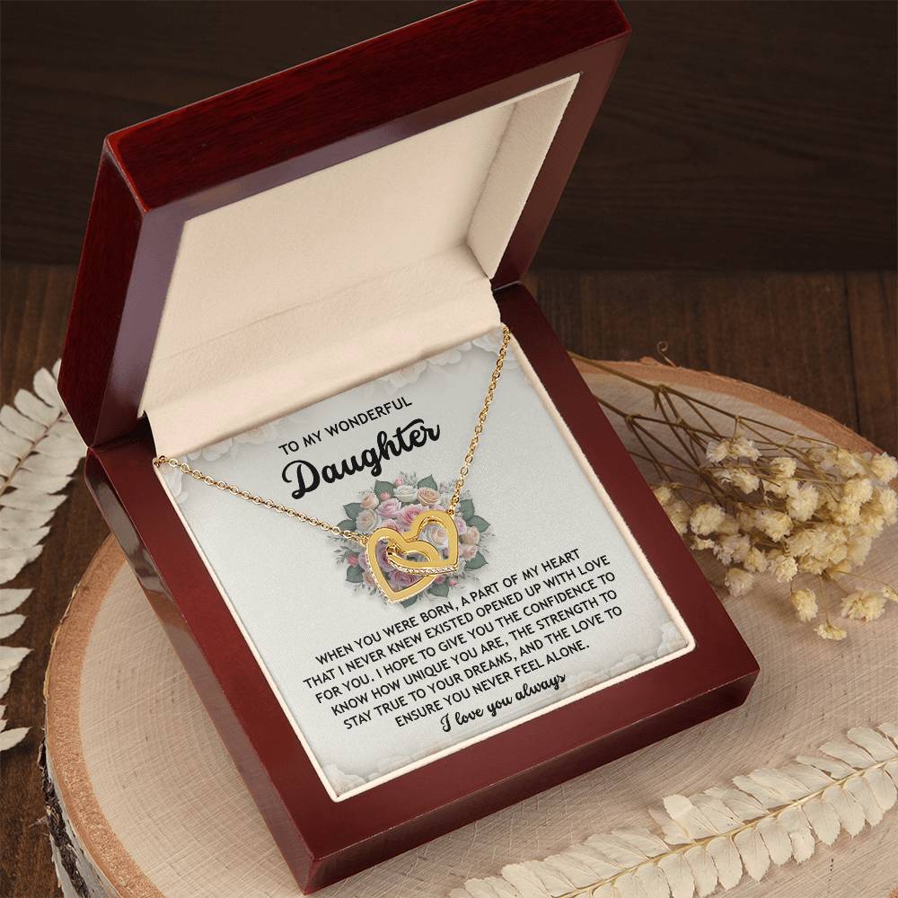 The Daughter-Stay True Interlocking Hearts Necklace, featuring cubic zirconia on a gold and silver design with a rose gold finish, rests in an open wooden jewelry box. An inscription for a daughter completes it inside the lid.