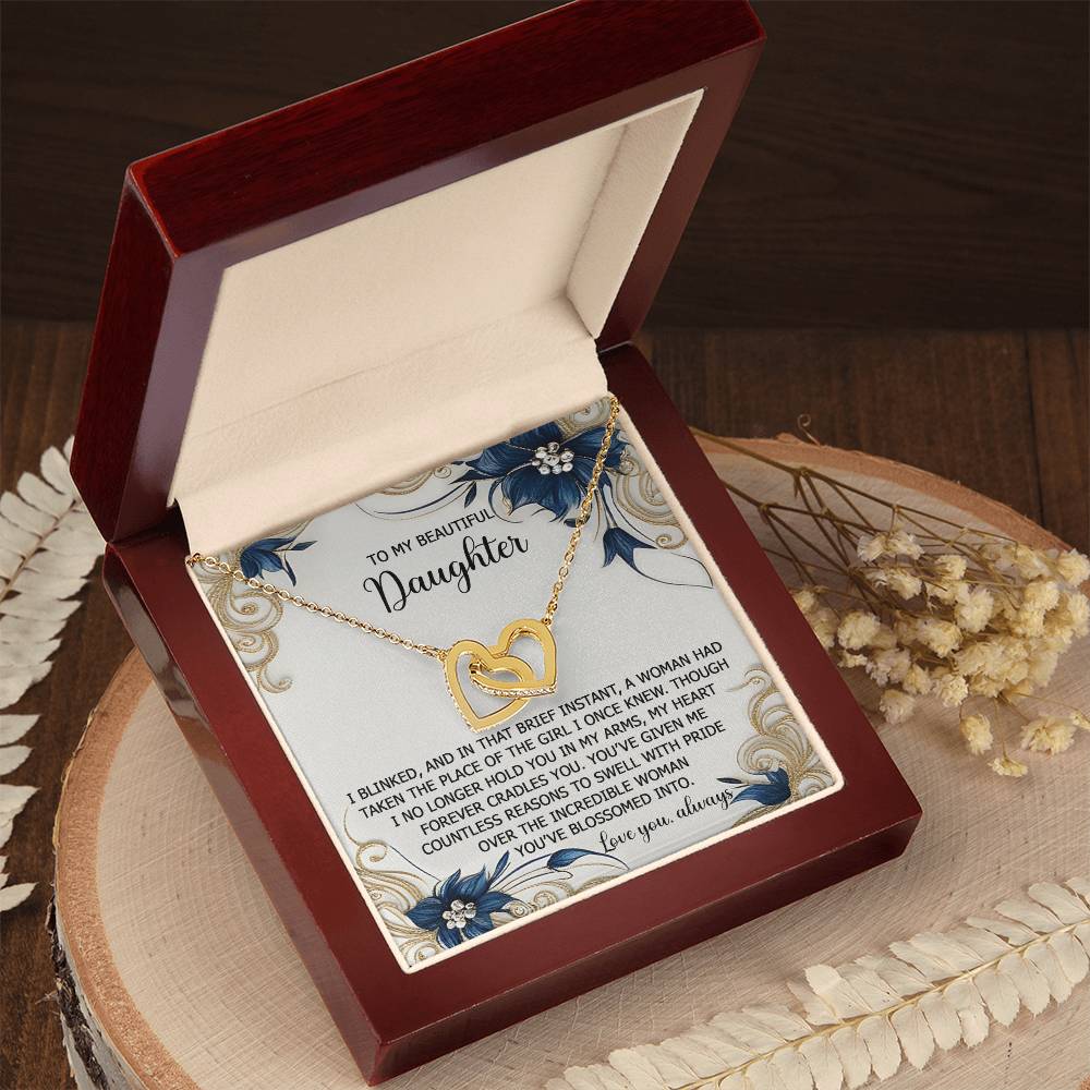 The Daughter-In My Arms - Interlocking Hearts Necklace comes in a wooden box with a heartfelt message for a daughter, featuring floral designs and cubic zirconia crystals.
