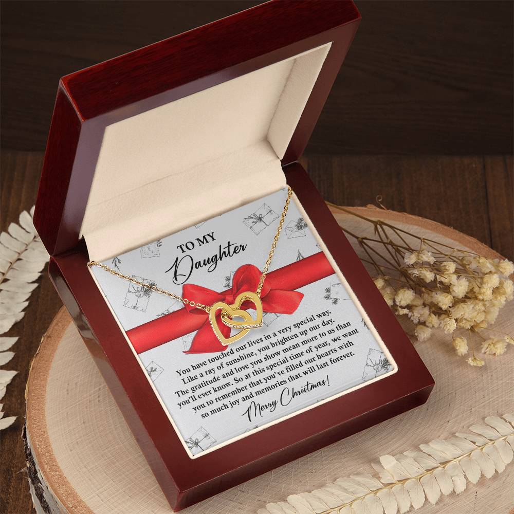 An elegant Daughter-Special Way - Interlocking Hearts Necklace, featuring a heart-shaped pendant embellished with sparkling cubic zirconia crystals, rests beautifully in an open jewelry box. The inside cover displays a note titled "To My Daughter," encapsulating the essence of love and connection.