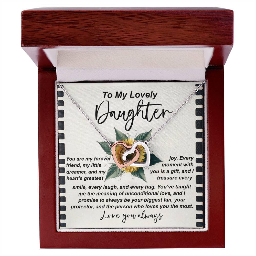 An open jewelry box displays the Daughter-Little Dreamer - Interlocking Hearts Necklace, featuring intertwined gold and silver hearts adorned with cubic zirconia crystals. It includes a heartfelt message expressing love, joy, and appreciation for a daughter.