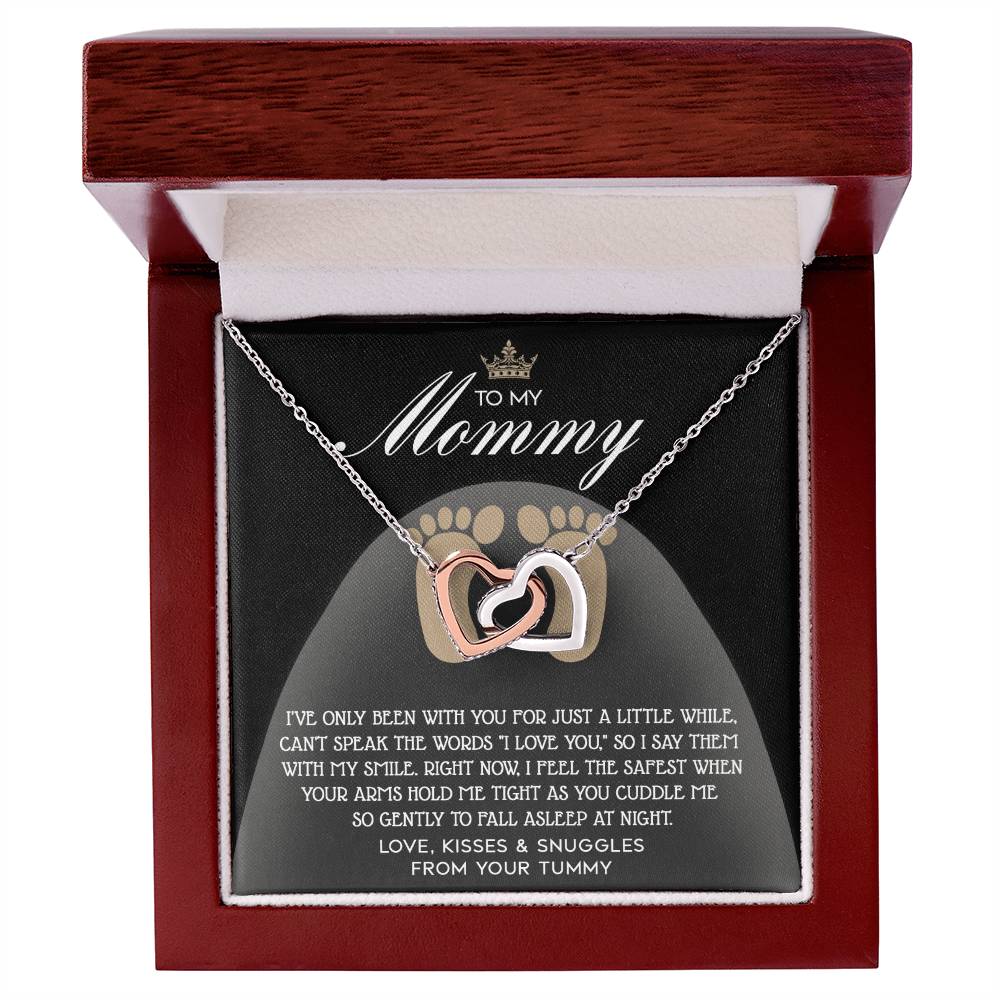 The "To Mama To Be, I Love You - Interlocking Hearts Necklace" with shimmering cubic zirconia crystals and a dazzling rose gold finish rests in its jewelry box, accompanied by a heartfelt note for "Mommy," adding an extra touch of love.