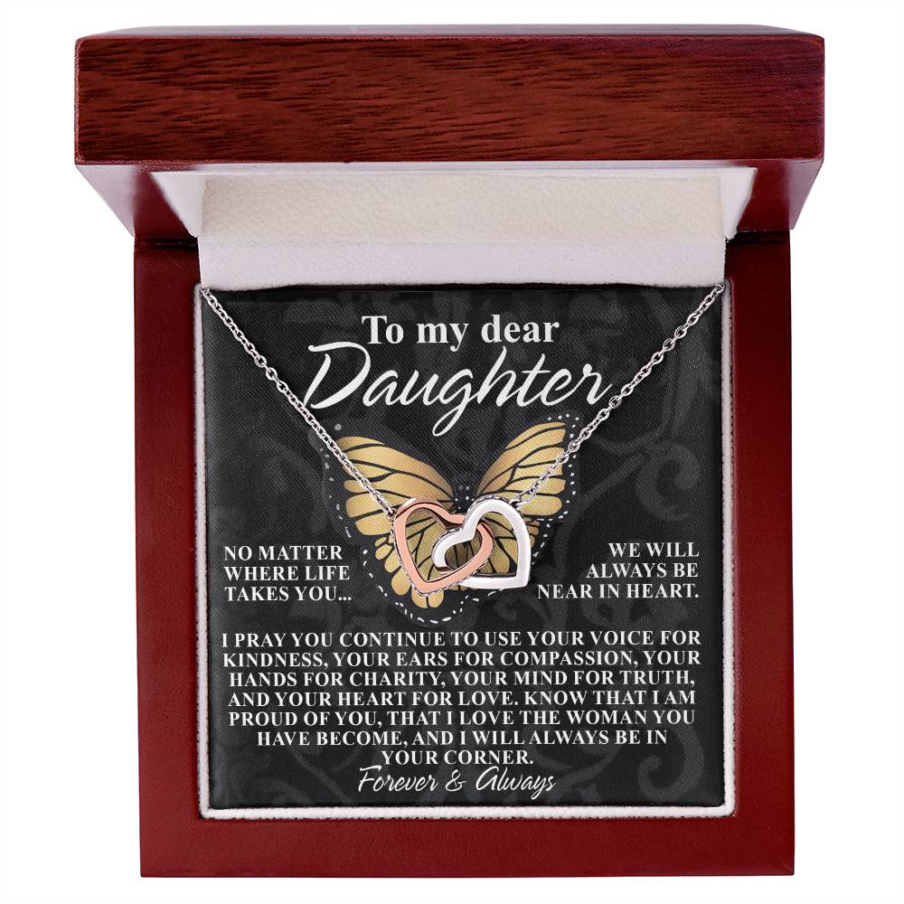 The Interlocking Hearts necklace, gold and silver with cubic zirconia crystals, is displayed in a wooden box. The message says: "To my dear Daughter, no matter where life takes you, we will always be near in heart." Product: Daughter-In Your Corner - Interlocking Hearts Necklace.
