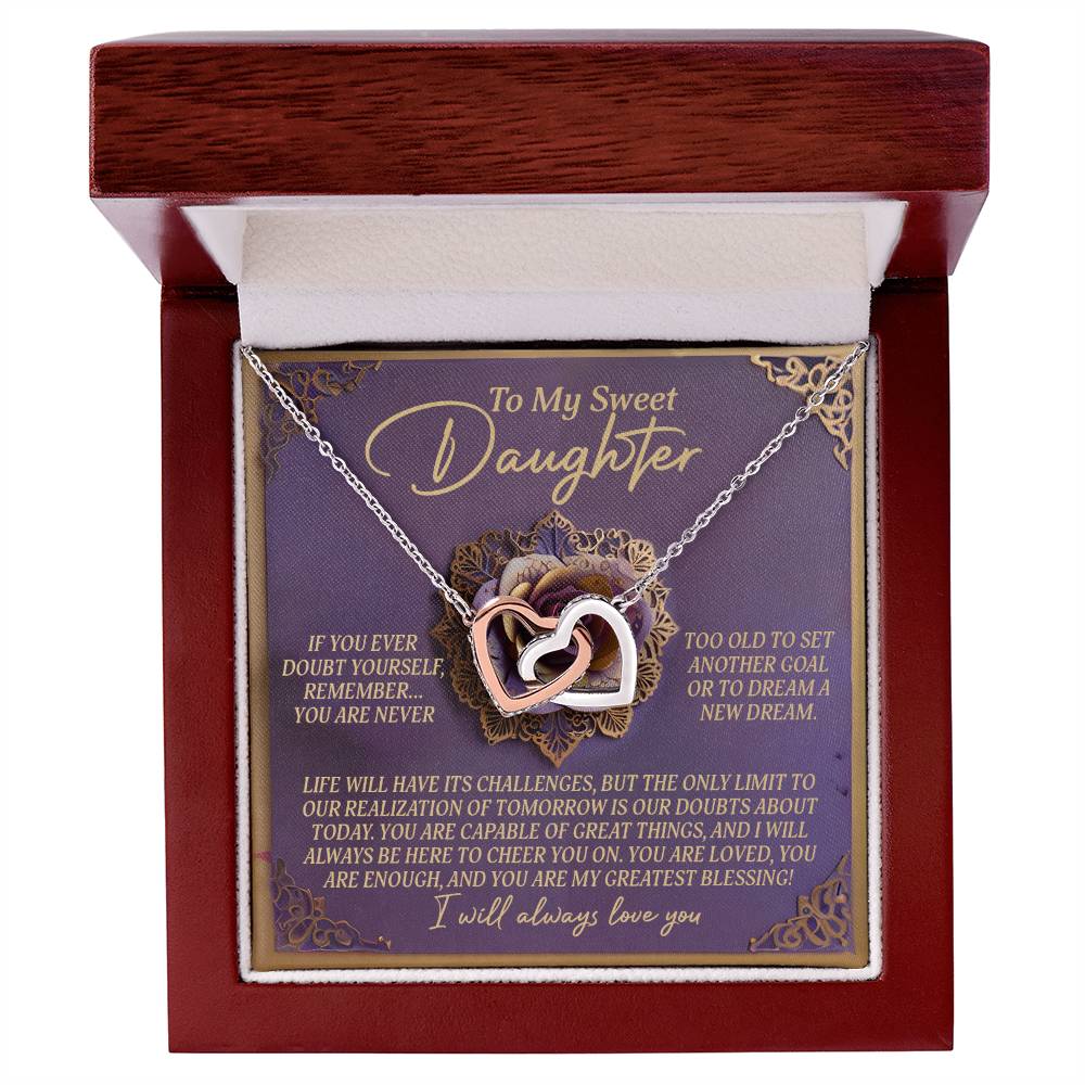 The Daughter-Greatest Blessing - Interlocking Hearts Necklace, with a rose gold finish, is elegantly presented in a wooden box. Inside, the message "To My Sweet Daughter" expresses love and support, enhanced with floral accents and sparkling cubic zirconia crystals.