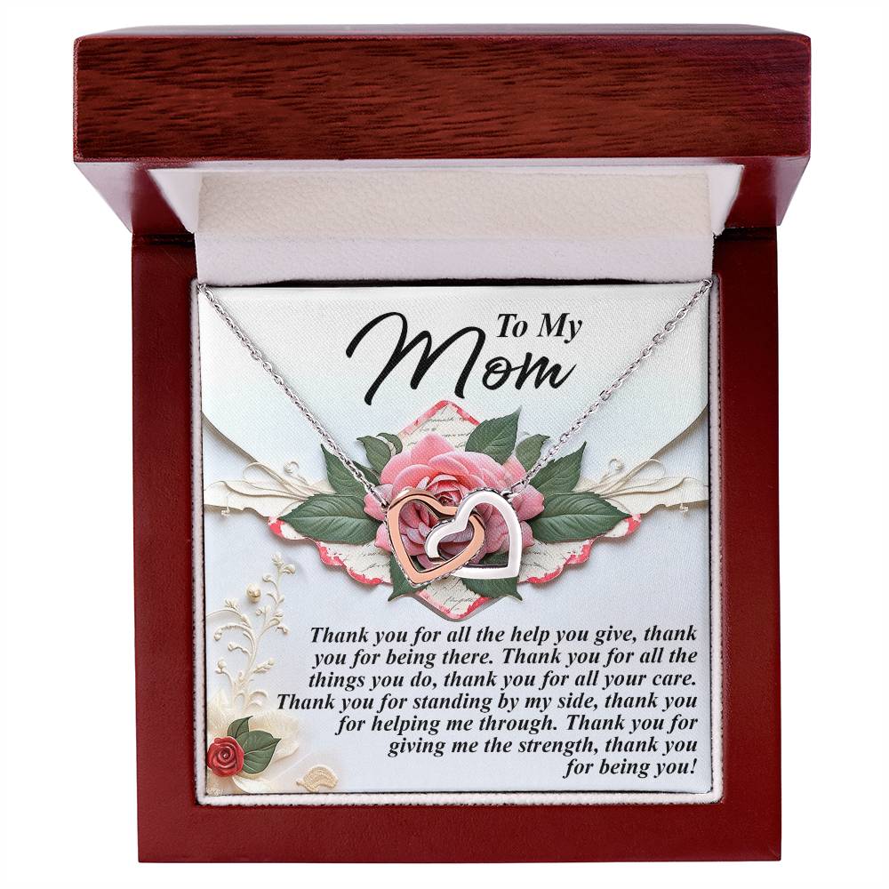 A Mom-Being You - Interlocking Hearts Necklace with a rose gold finish is displayed in an open jewelry box. The card inside reads: "To My Mom," expressing gratitude for her support and strength, while pink roses and green leaves on the card enhance the elegance of the dark wooden box.