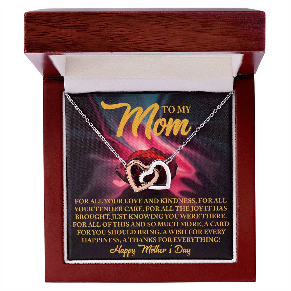 The Mom-Tender Care - Interlocking Hearts Necklace, adorned with cubic zirconia crystals, comes in a wooden box featuring the heartfelt message: "To My Mom. For all your love and kindness... A wish for every happiness, a thanks for everything! Happy Mother's Day." An ideal gift for her.