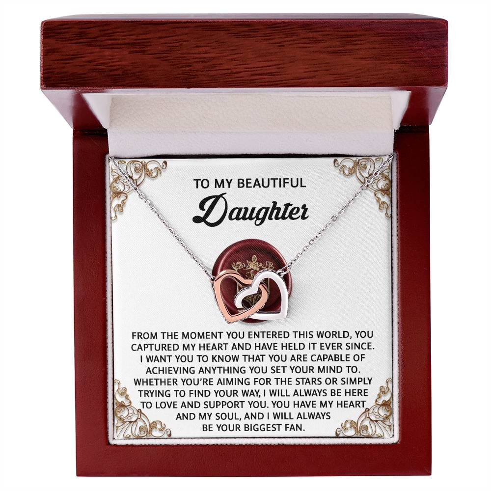The Daughter-Biggest Fan Interlocking Hearts Necklace comes in a wooden box with a heartfelt message, featuring cubic zirconia crystals and a silver chain.