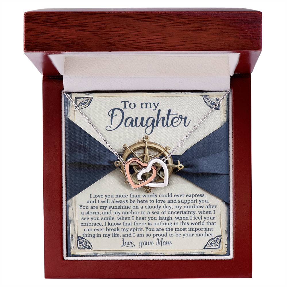 A jewelry box features the Daughter-Sunshine Anchor - Interlocking Hearts Necklace in rose gold, with cubic zirconia and a compass design. Accompanied by a heartfelt letter to her daughter, from mom, expressing love and support, adorned with decorative corners.