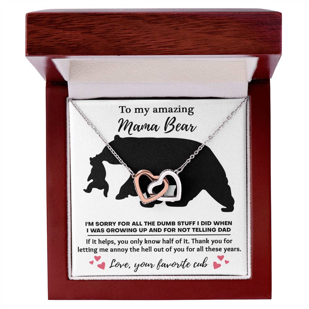 The "To Mom, Not Telling Dad" Interlocking Hearts Necklace, adorned with cubic zirconia crystals, comes in a wooden box. Text reads: "To my amazing Mama Bear... Love, your favorite cub.