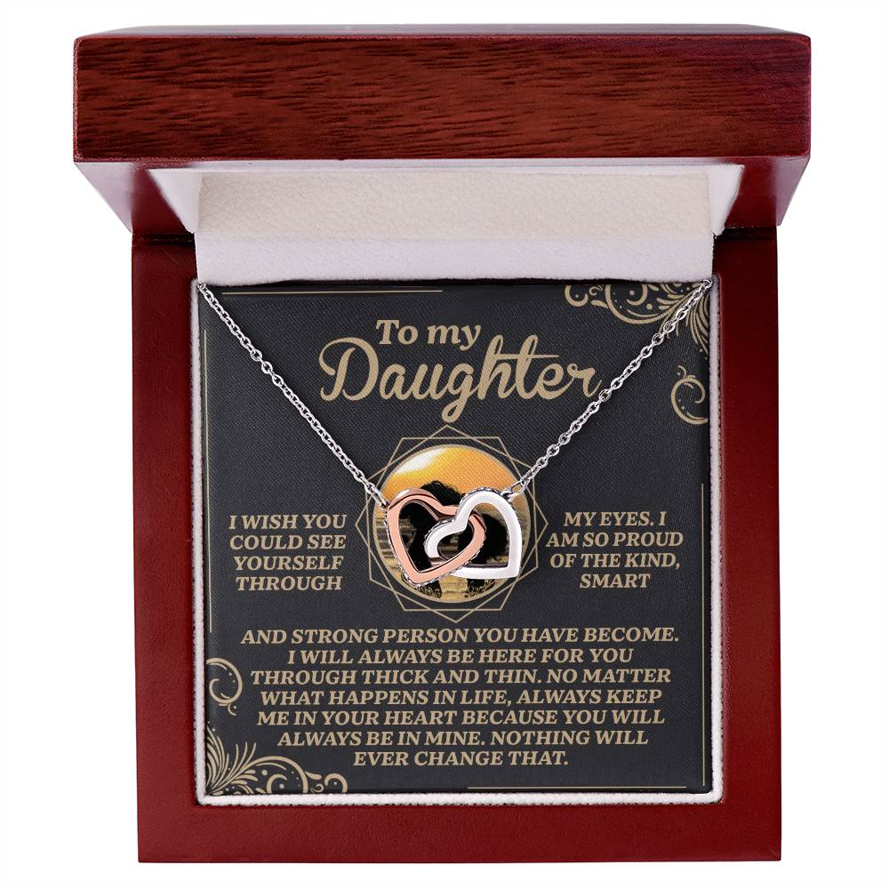 The Daughter-Proud Heart necklace, with a rose gold finish and sparkling cubic zirconia crystals, is elegantly presented in an open wooden box with a heartfelt message expressing pride, love, and unwavering support for a daughter.