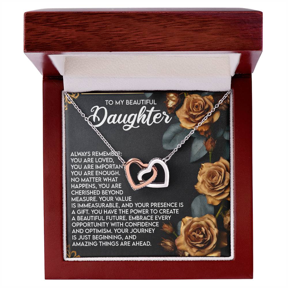 The Daughter-Loved Enough - Interlocking Hearts Necklace, with a rose gold finish and cubic zirconia crystals, is presented in an open, wood-finished box. It includes a heartfelt message for a daughter and is beautifully adorned with rose illustrations.