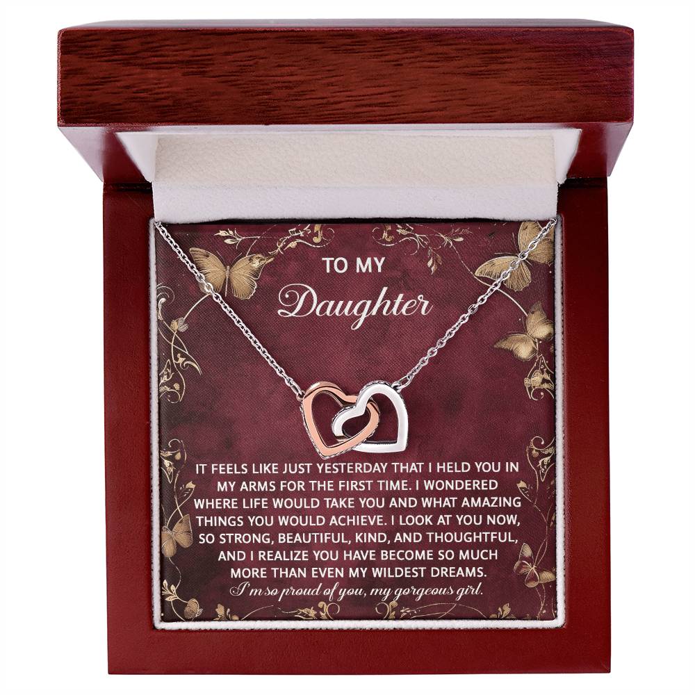 The Daughter-Wildest Dreams - Interlocking Hearts Necklace features rose gold finish and cubic zirconia crystals. It comes in a wooden box with an affectionate message, enhancing its sentimental value for your daughter.
