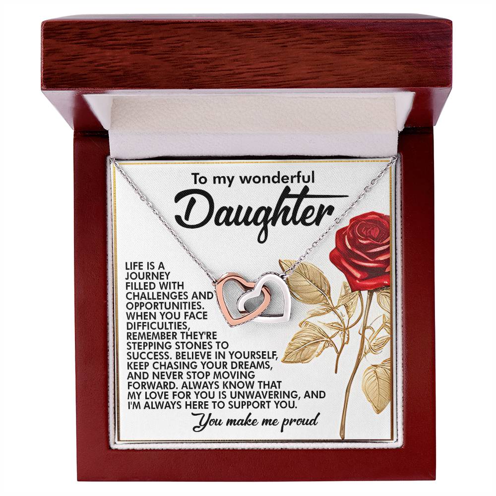 The Daughter-Journey Challenges Interlocking Hearts Necklace, featuring a rose gold finish, comes in a jewelry box with a heartfelt message for a daughter. The lid includes text and a red rose graphic. The wooden exterior and velvet interior enhance the elegance of this meaningful gift.