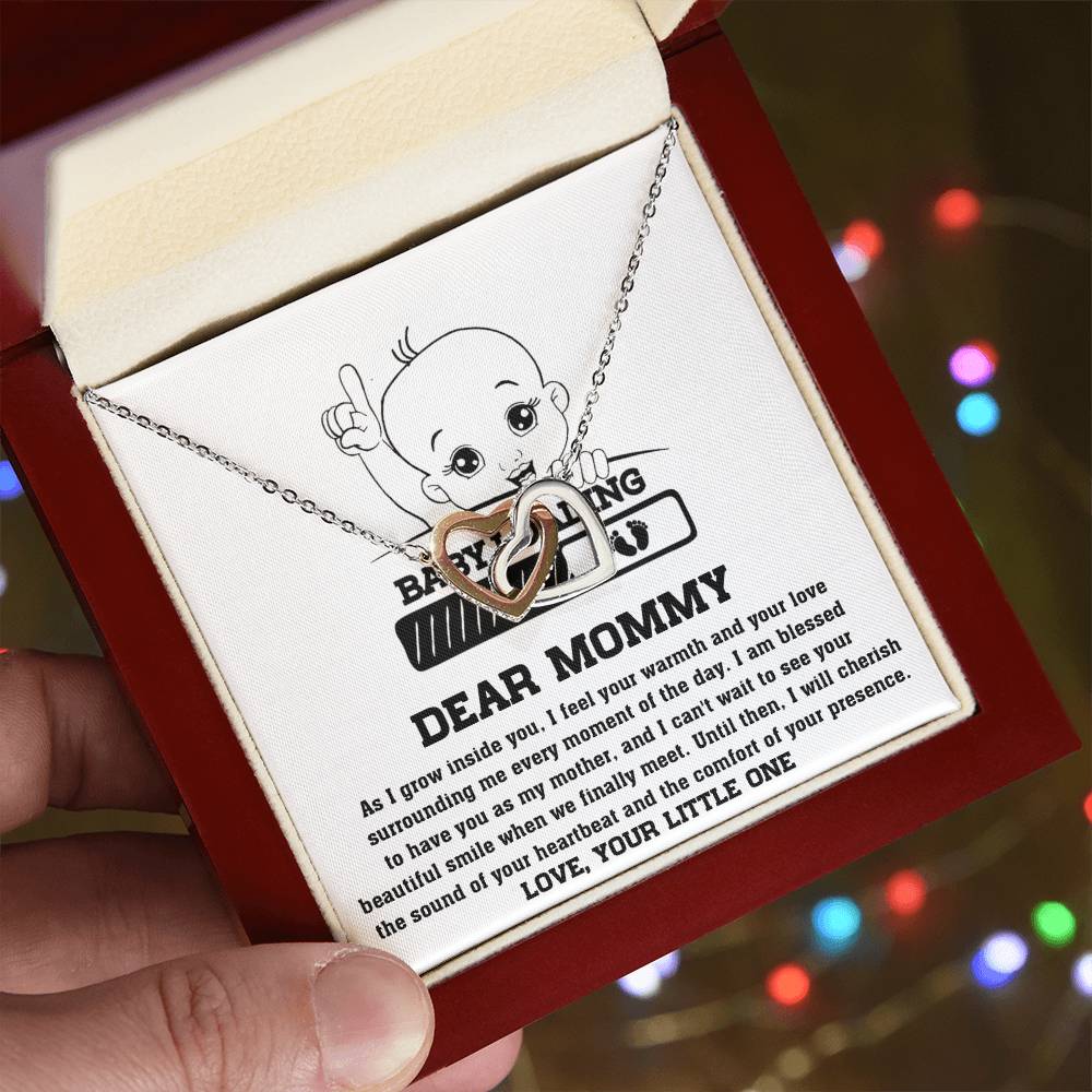 A hand holding a red box with a ShineOn Fulfillment Interlocking Hearts necklace and a pendant featuring a baby figure and an inscription for a mother.