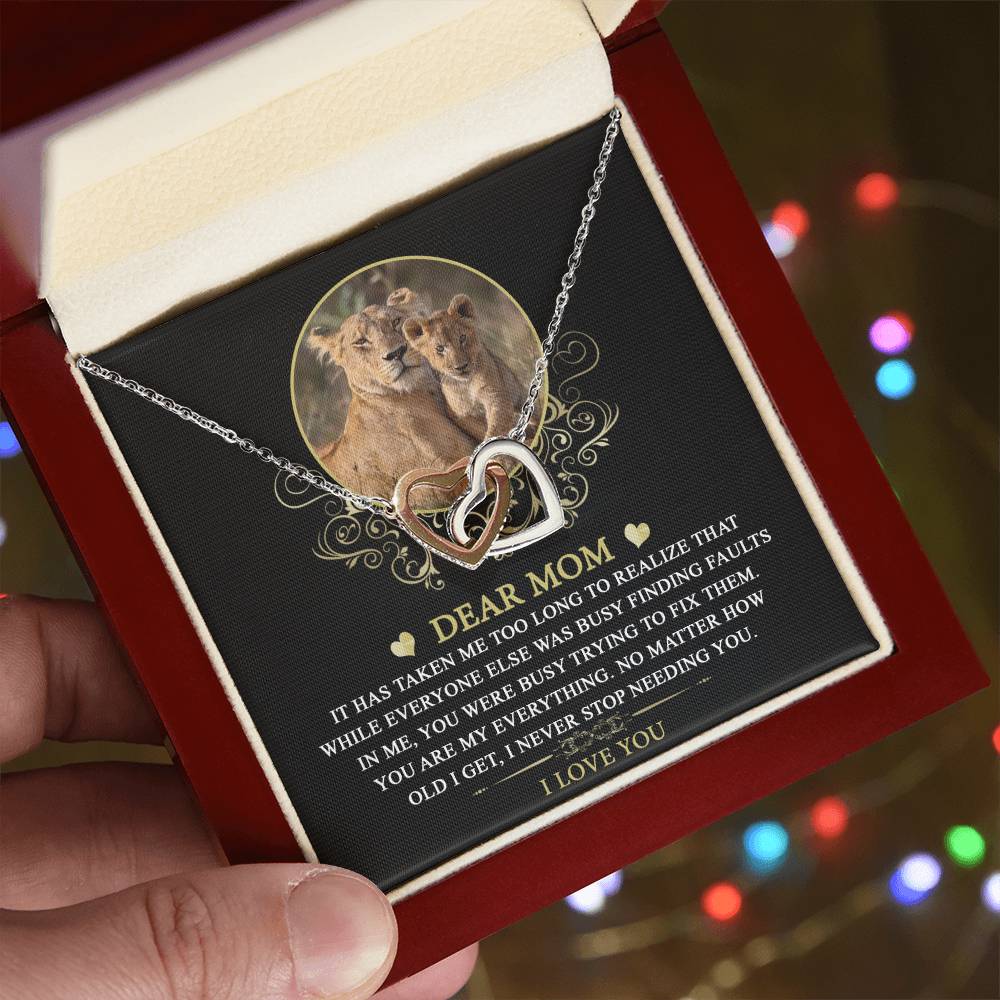 The "To Mom, My Everything" Interlocking Hearts Necklace is elegantly presented with a lioness and cubs image and bokeh lights. Embellished with cubic zirconia crystals, this personalized gift conveys elegance and love along with a heartfelt message for mothers.