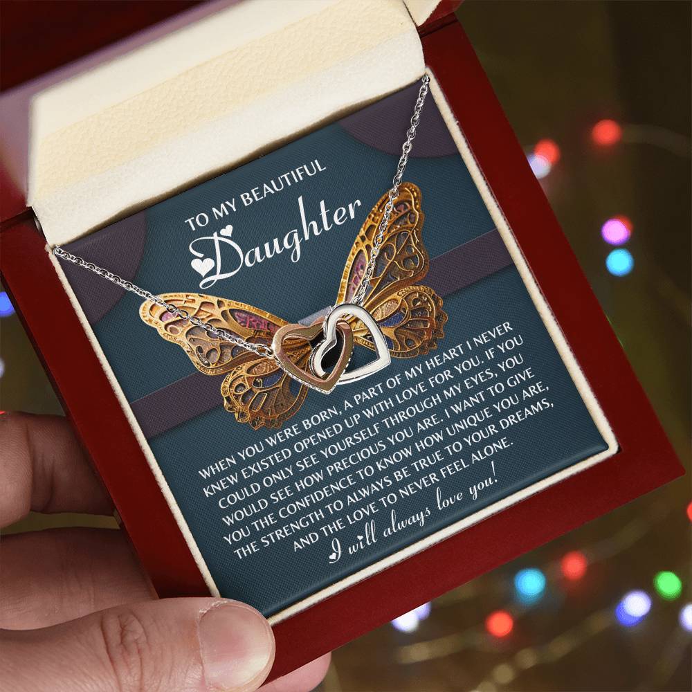 The "Daughter-Never Feel Alone" Interlocking Hearts Necklace, embellished with cubic zirconia crystals, rests beautifully in an open gift box alongside a heartfelt message for a daughter.