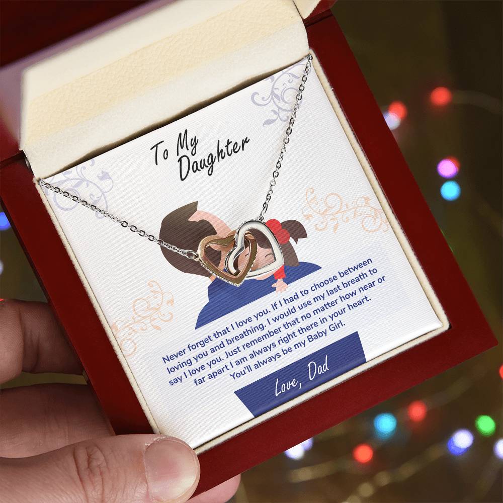 A hand holding a box with a To My Daughter, You_ll Always Be My Baby Girl - Interlocking Hearts Necklace adorned with cubic zirconia crystals and a heartfelt message from ShineOn Fulfillment to a daughter.