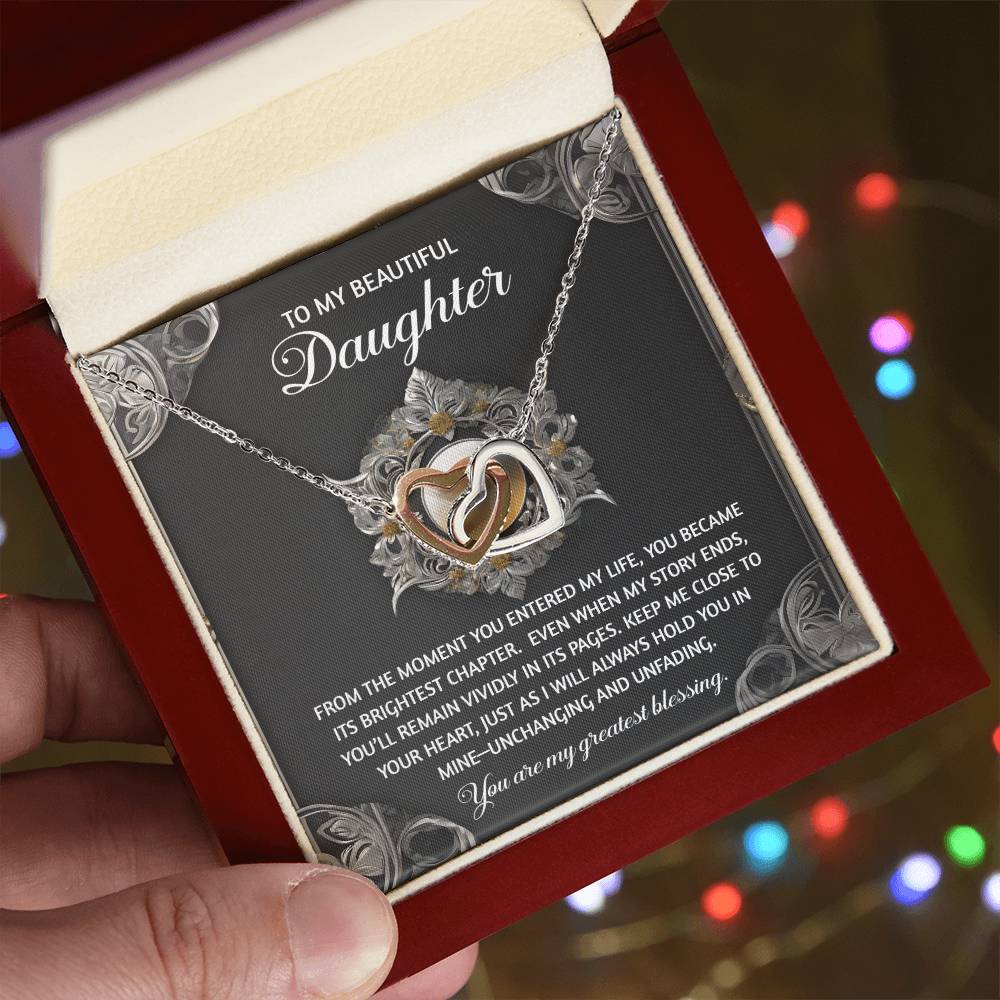 The Daughter-Greatest Blessing - Interlocking Hearts Necklace, embellished with cubic zirconia crystals, lies elegantly in a jewelry box accompanied by a heartfelt message card titled "To My Beautiful Daughter," exuding love and charm.