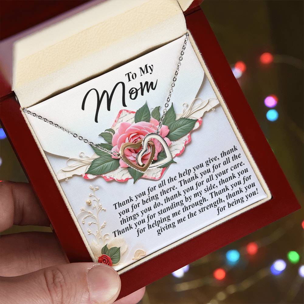 A hand presents an open jewelry box showcasing the "Mom-Being You - Interlocking Hearts Necklace." Inside, a floral design complements a heartfelt message thanking a mother for her love, support, and strength.
