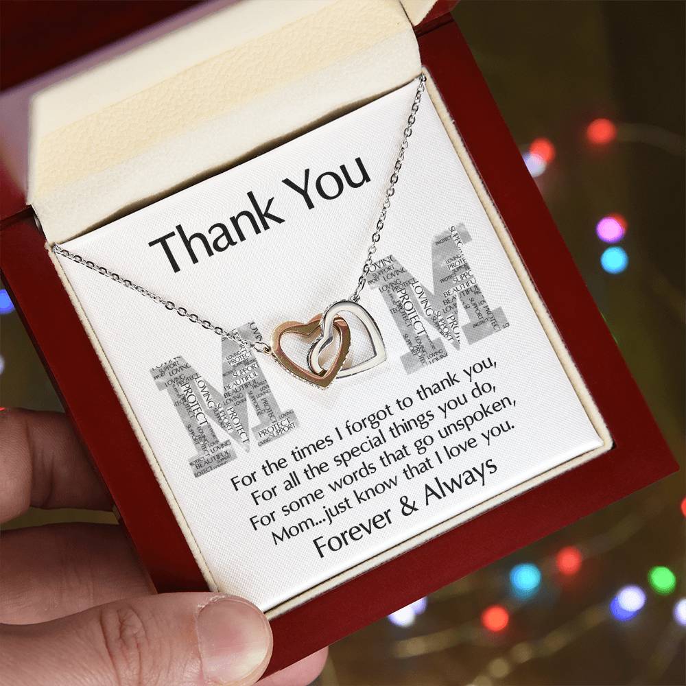 The "To Mom, Thank You" Interlocking Hearts Necklace, adorned with cubic zirconia crystals, comes in a box labeled "Thank You Mom," with a heartfelt message and held by a hand. This personalized gift perfectly expresses love and gratitude.
