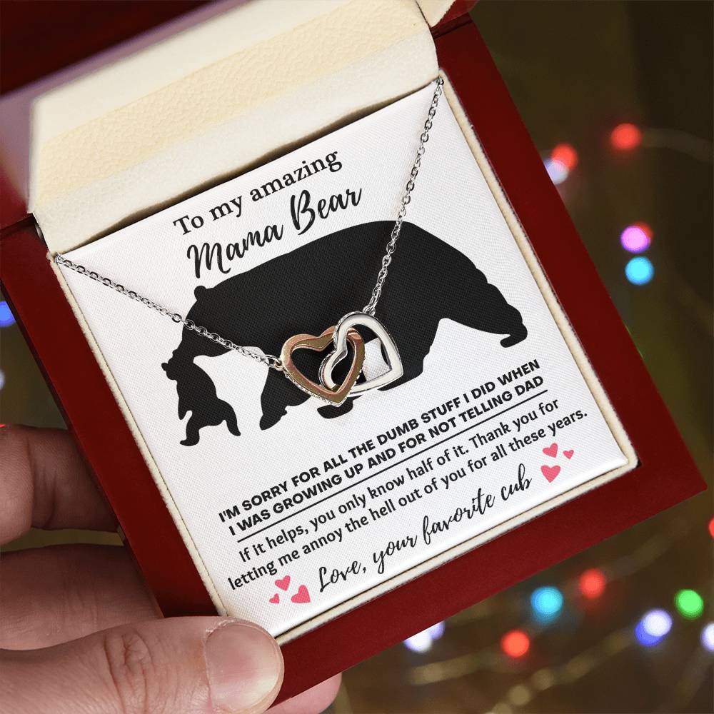 The "To Mom, Not Telling Dad - Interlocking Hearts Necklace" features shimmering cubic zirconia crystals and is presented in a box with a heartfelt note to "Mama Bear," expressing love and apologies from her favorite cub.