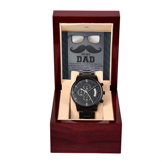 A black chronograph watch with a stainless steel case in a wooden box, featuring an insert with a mustache image and a message to To Dad, Learned From You.