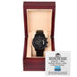 A "To Dad, Financial Burden - Metal Chronograph Watch" with a day and date display is placed inside an open wooden watch box. The inside cover of the box has a humorous message that reads, "Bank of Dad: Voted No. 1 Most Reliable Money Lender.