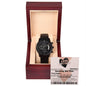 A black "To Husband, Jackpot Winner - Metal Chronograph Watch" displayed in an open wooden box. Behind the watch is a card with the text "Love Lottery" and "Smoking Hot Wife.