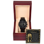 A black chronograph watch with multiple dials is displayed inside a wooden box. A message card titled "To Husband, Make Us Strong - Metal Chronograph Watch" is placed beside it.