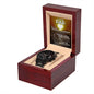 A black chronograph wristwatch presented in an open wooden gift box with a "To Dad, My Guiding Light" message displayed inside the lid.