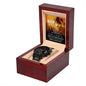 A black chronograph watch with a copper dial is elegantly displayed in an open wooden box. Inside the lid, a partially visible message featuring a lion image and text addressed to "Dad" adds a personal touch to this "To Dad, Repay Your Love - Metal Chronograph Watch".