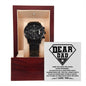 A "To Dad, Been My Hero" metal chronograph watch with a black strap and dial in a wooden box, under a lid displaying a message titled "Dear Dad.