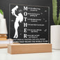 A Mother Acronym Acrylic Plaque with a poem about a mother, featuring a silhouette of a mother and child, displayed on a wooden stand against a plant backdrop—perfect as a Mother's Day gift.