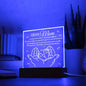 Sentence with Product Name: An "To Mom, Your Little One - Gift For Mom" acrylic plaque with a heartfelt message to a mother, featuring an illustration of two hands cradling smaller pair, displayed on a wooden stand.