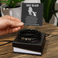 A hand presenting a gift box containing the "To Dad, The Man - Love You Forever" bracelet with a "my dad" poem printed on the box lid.
