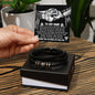 A hand gracefully holds a card above a gift box showcasing the "My Man-My Shelter - Love You Forever Bracelet," made of vegan leather. The card reads "To My Man" and features an illustration of a couple holding hands.