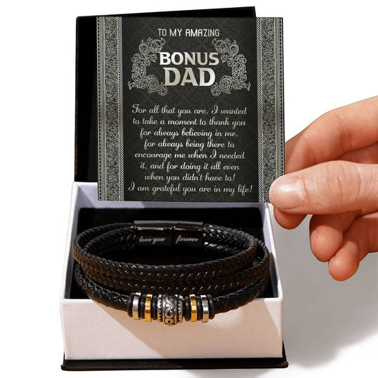 A hand holding a gift box containing a "To Dad, In My Life" bracelet with a metal clasp, accompanied by a card expressing gratitude to a father.