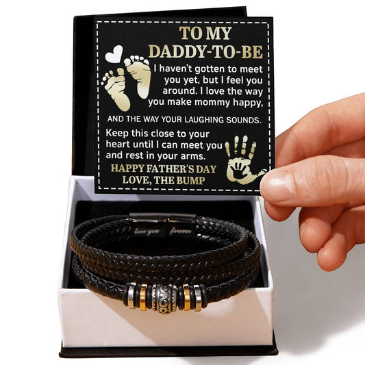 A hand presents an open gift box containing a To Dad, Feel You Around - Love You Forever Bracelet and a father’s day card addressed to a "daddy-to-be" with a heartfelt message.