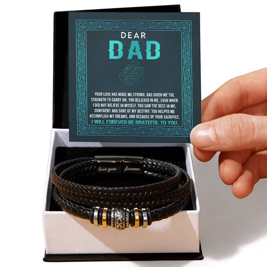 A hand holds a "To Dad, Grateful To You" bracelet next to a box containing a card with a heartfelt message to a dad.