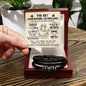 A card for an "Awesome Husband" is held by hand, and below it, the "To My Husband, Battle For You - Love You Forever Bracelet" rests elegantly inside a wooden box.