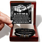 A hand holds a card reading "To My Man" above the My Man-My Shelter - Love You Forever Bracelet, nestled in a red box. Crafted from braided vegan leather with metallic accents, it makes a perfect gift for him.