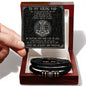 A hand holding a card with a message "To My Viking Dad" above a black vegan leather braided men's bracelet with metal beads and an engraved message in an open box.
