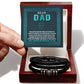 A hand holds a "To Dad, Grateful To You" bracelet next to a box containing a card with a heartfelt message to a dad.