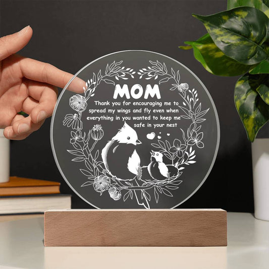 A translucent circular glass plate with a leaf pattern at the edges, displayed upright on a wooden LED base against a white background.