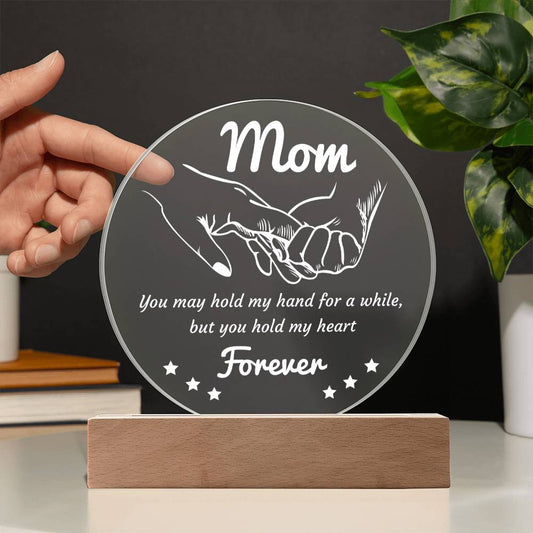 A round, translucent To Mom, Hold My Hand - Acrylic Circle Plaque with subtle etchings, mounted on a rectangular wooden LED base, isolated on a white background.