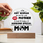 A hand holds the "To Mom, Someone Special Acrylic Circle Plaque" with the text: "Any woman can be a mother, but it takes someone special to be called mom." Ideal for special occasions, it rests elegantly on a wooden stand beside a plant.