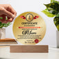 The "To Mom, World's Most Marvelous Mom Acrylic Circle Plaque," expertly crafted from high-quality acrylic, sits elegantly on a wooden stand with decorative text and graphics. A hand and plant are visible in the background, making it the perfect gift.