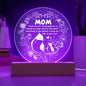 A translucent circular glass plate with a leaf pattern at the edges, displayed upright on a wooden LED base against a white background.