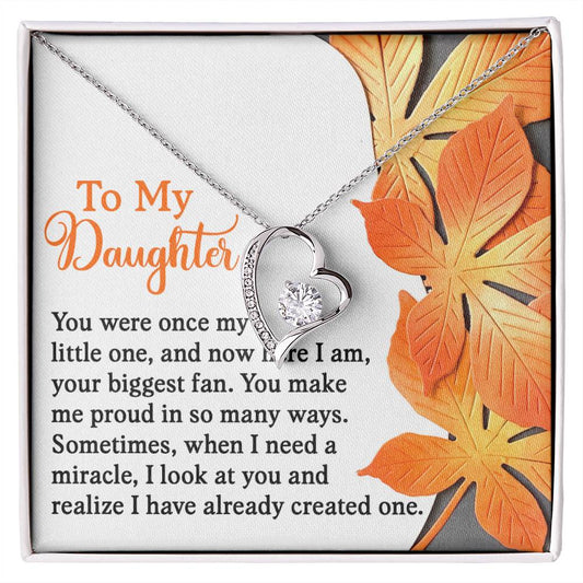 The Daughter-Here I Am - Forever Love Necklace, featuring a heart-shaped pendant with a white gold finish and sparkling CZ crystal, is beautifully displayed on a card adorned with an autumn leaf design and an affectionate message to a daughter.