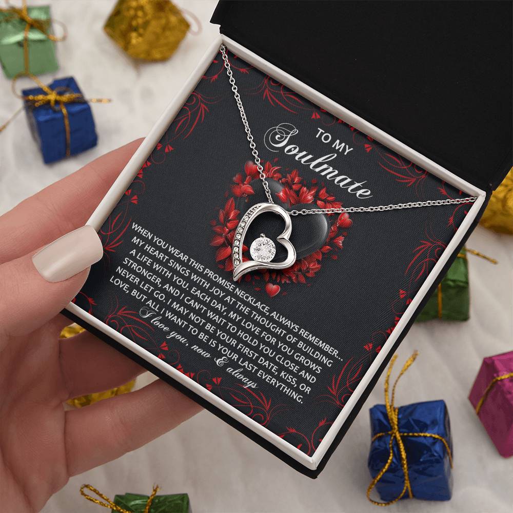 The Soulmate-Hold You Close - Forever Love Necklace, a heart-shaped pendant in a box with a heartfelt message, shimmers with cubic zirconia crystals and a gold finish. It nestles among small, wrapped gifts.
